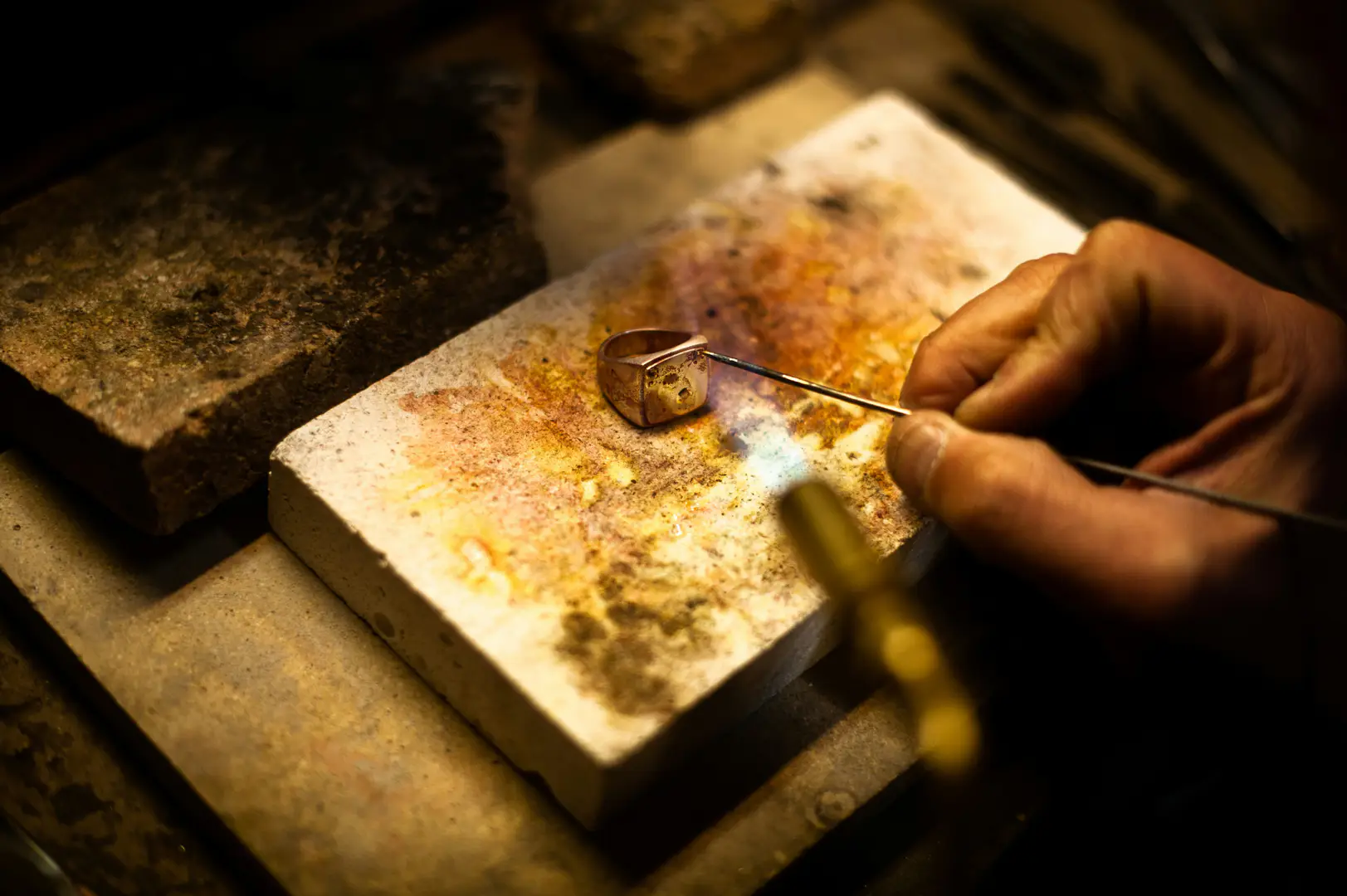 Joyero reparando un anillo de oro en su banco de trabajo, en un taller de joyería y relojería