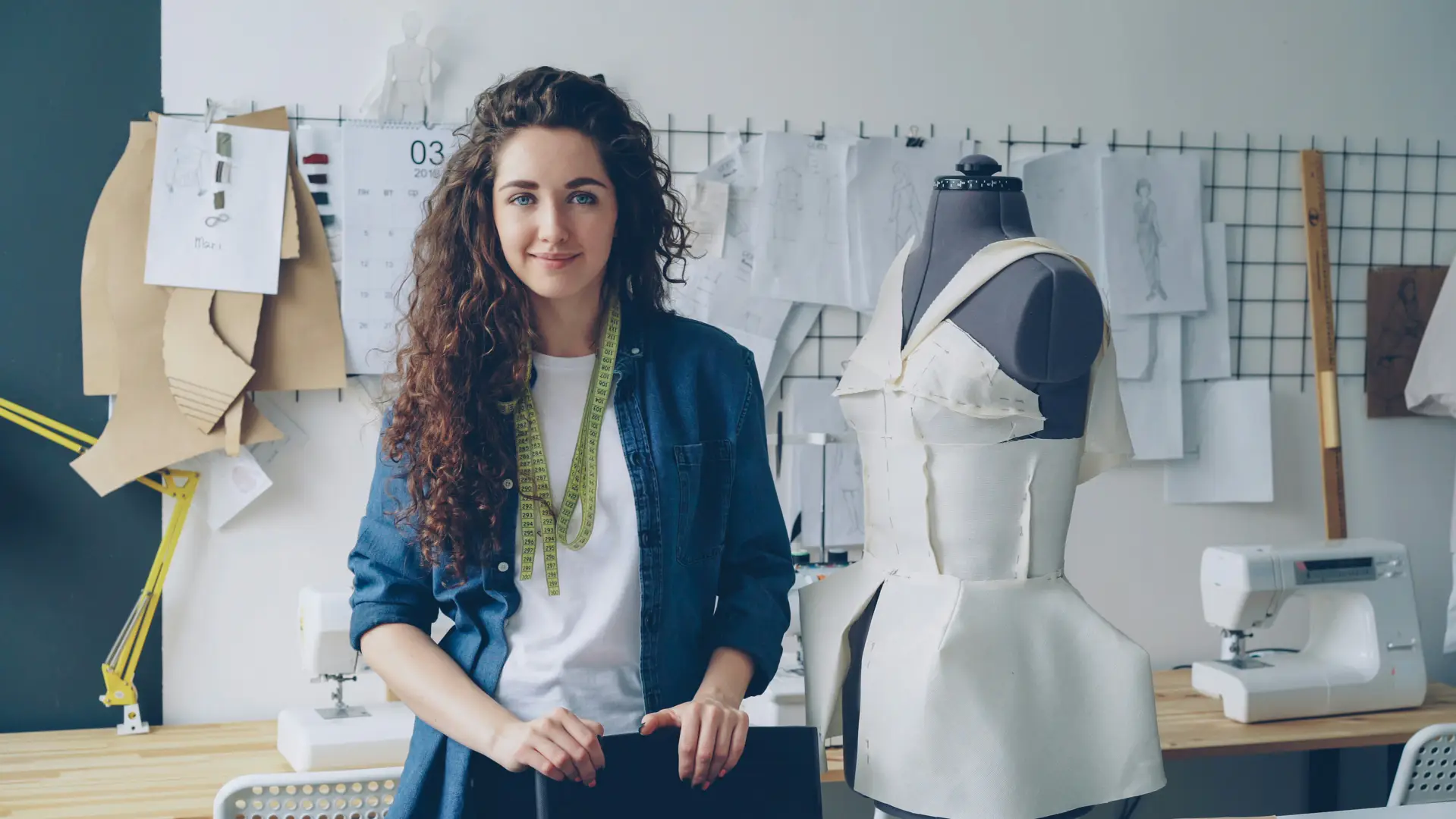 Dueña de una sastrería en su taller, rodeada de patrones, maniquí y máquinas de coser